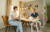 Two people enjoying breakfast at a dining table in Veranda chalet at Camping Sevink Molen, Netherlands.