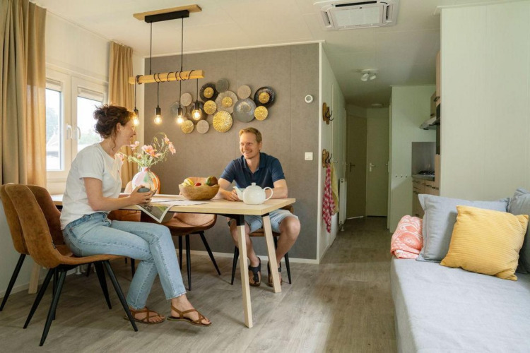 Dos personas conversan y disfrutan en un luminoso chalet con decoración moderna en Camping Sevink Molen.