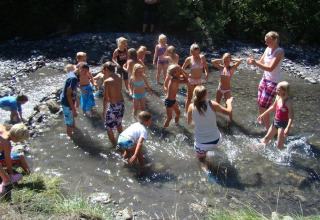 Kinder spielen an einem sonnigen Tag im flachen Wasser bei Camping Lou Passavous in Südfrankreich.