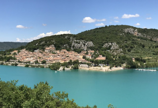 Udsigt over en charmerende landsby og turkisblåt vand ved Camping Lou Passavous i Provence-Alpes-Côte d’Azur.