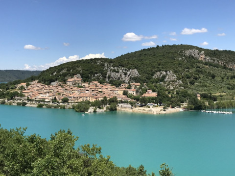 Zicht op een schilderachtig dorp en turquoise water bij Camping Lou Passavous in Provence-Alpes-Côte d’Azur.