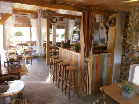 Acogedora zona común en Camping Lou Passavous con muebles de madera y cortinas claras en Provenza.