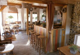 Cozy communal dining area at Camping Lou Passavous with wooden furnishings and light curtains in Provence.