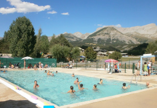Piscina all'aperto al Camping Lou Passavous, persone che nuotano e vista sulle montagne delle Alpi.