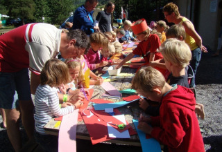 Kinder und Erwachsene basteln draußen im Ferienpark Camping Lou Passavous in Provence-Alpes-Côte d’Azur, Frankreich.