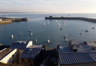 Vue sur un port avec des bateaux depuis Camping O2, parc de vacances en Normandie, France, toits au premier plan.