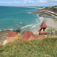 Udsigt over stranden og det blå hav nær Longueville i Normandiet, Frankrig, med en bygning ved kysten.