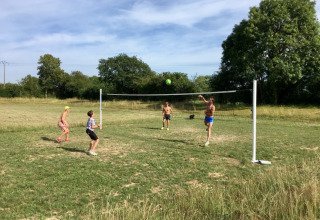 Four people are playing outdoor volleyball on the grass at Camping O2 holiday park in Normandy, France.