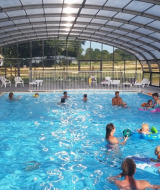 Piscina coperta con famiglie che nuotano e giocano al Camping O2, villaggio vacanze in Normandia, Francia.