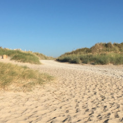 Sandsti ved klitterne og blå himmel på Camping O2-ferieparken i Normandiet, Frankrig, en rolig dag.