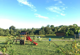 Legeplads ved Camping O2, feriepark i Normandiet, Frankrig, med rutsjebane og grønt landskab.