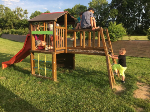 Bambini giocano su un parco giochi con scivolo e struttura da arrampicata presso Camping O2 in Normandia, Francia.