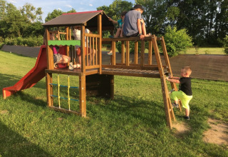 Bambini giocano su un parco giochi con scivolo e struttura da arrampicata presso Camping O2 in Normandia, Francia.