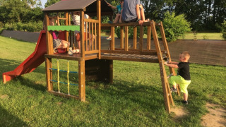 Børn leger på en legeplads med rutsjebane og klatrestativ på Camping O2, et feriested i Normandiet, Frankrig.