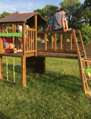 Bambini giocano su un parco giochi con scivolo e struttura da arrampicata presso Camping O2 in Normandia, Francia.
