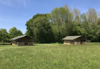 To safaritelt på en grøn eng ved Camping O2-feriepark i Normandiet, Frankrig, på en solrig dag.