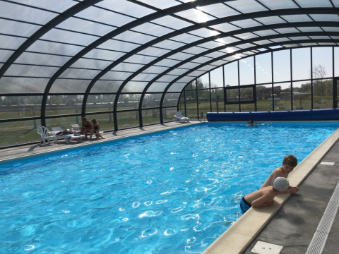 Piscina cubierta en Camping O2 en Normandía, Francia, con niños nadando y adultos descansando alrededor.