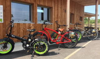 Biciclette elettriche colorate a noleggio davanti a un edificio in legno al Camping O2 in Normandia, Francia.
