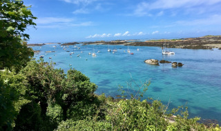 Både flyder på det klare blå vand omgivet af grøn vegetation nær Longueville i Normandiet, Frankrig.