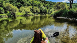 Vrouw kajakt op een heldere rivier omgeven door bos bij Camping du Rivage, Diekirch, Luxemburg.