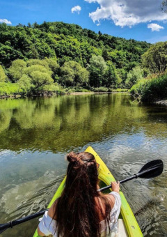 Mujer en kayak remando por un río rodeado de bosque en Camping du Rivage, Diekirch, Luxemburgo.