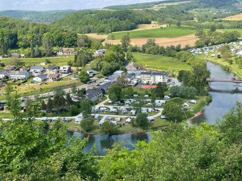 Vista aerea di Camping du Rivage a Diekirch, Lussemburgo, con caravan, fiume, ponte e vegetazione rigogliosa.