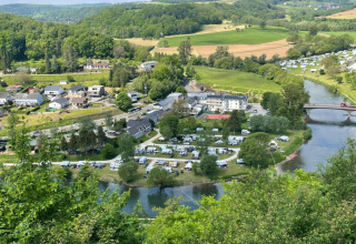 Vista aerea di Camping du Rivage a Diekirch, Lussemburgo, con caravan, fiume, ponte e vegetazione rigogliosa.