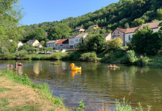 Folk nyder kanoer og en oppustelig and på en flod ved Camping du Rivage i Diekirch, Luxembourg.