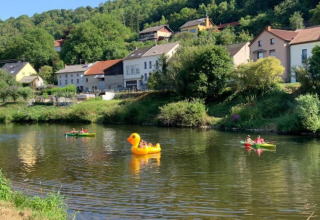 Mensen genieten van waterpret op kano’s en een grote eend aan Camping du Rivage in Diekirch, Luxemburg.