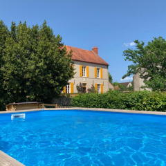 Piscina azul frente a una casa amarilla con contraventanas naranjas en Auvergne-Rhône-Alpes, Francia.