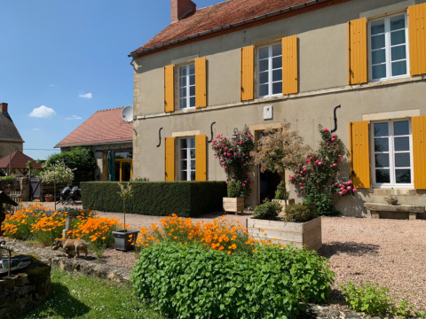 Charmerende feriepark Minicamping Sous les Cloches i Auvergne-Rhône-Alpes med farverige blomster og gulmalede skodder.