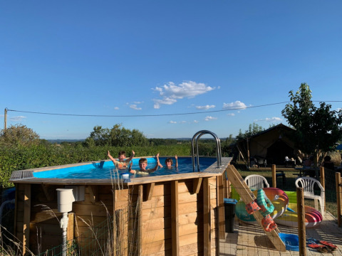 Kinder schwimmen in einem erhöhten Pool im Minicamping Sous les Cloches in Auvergne-Rhône-Alpes, Frankreich.