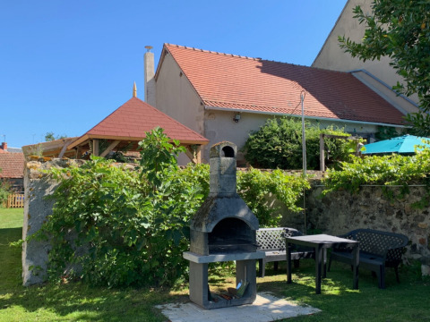 Zona de jardín al aire libre con barbacoa, mesas y sillas en Minicamping Sous les Cloches en Auvergne-Rhône-Alpes, Francia.