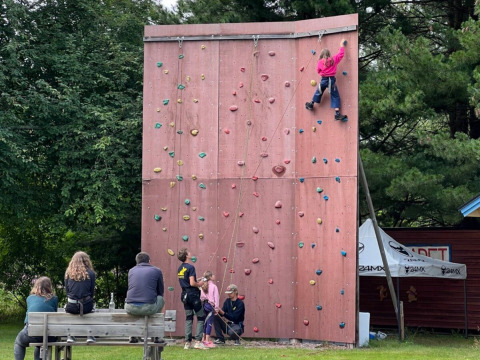 Bambini arrampicano su una parete al Camping Yttermalungs, parco vacanze a Dalarna, Svezia, con spettatori.