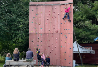 Børn klatrer på en klatrevæg på Camping Yttermalungs i Dalarna, Sverige, mens tilskuere ser på.