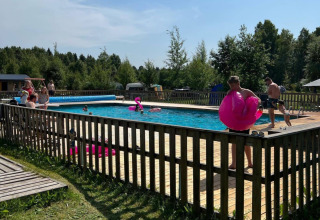 Folk nyder en solrig dag ved swimmingpoolen på Camping Yttermalungs feriepark i Dalarna, Sverige.