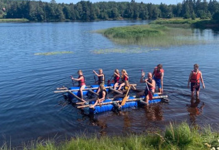 Group kayaking and rafting on the lake at Camping Yttermalungs holiday park in Dalarna, Sweden, sunny day.