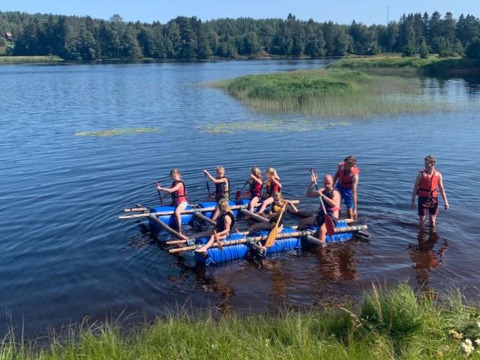 Gruppo che fa rafting sul lago al Camping Yttermalungs, parco vacanze in Dalarna, Svezia, giornata di sole.
