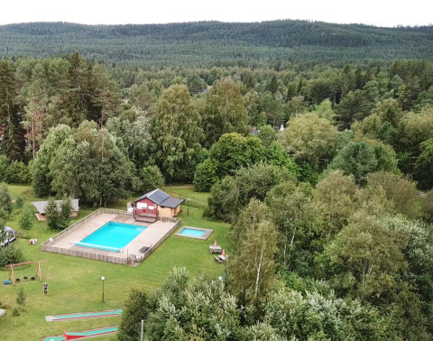Vue aérienne du Camping Yttermalungs à Dalarna, Suède, avec piscine, mini-golf et forêt en arrière-plan.