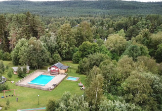 Vue aérienne du Camping Yttermalungs à Dalarna, Suède, avec piscine, mini-golf et forêt en arrière-plan.