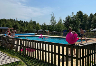 Persone che si godono una giornata di sole nella piscina recintata del Camping Yttermalungs a Dalarna, Svezia.