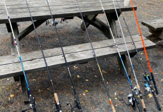 Canne da pesca disposte vicino a un tavolo da picnic al Camping Yttermalungs in Dalarna, Svezia.