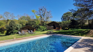 Piscina al aire libre con tumbonas y cabañas de madera en Domaine La Sauzette, parque vacacional Occitanie.