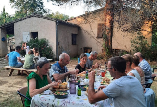 Cena al aire libre en Domaine La Sauzette, parque vacacional en Occitanie, Francia, con huéspedes compartiendo.