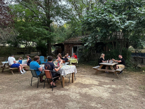 Personas comiendo al aire libre en Domaine La Sauzette, rodeados de árboles en Occitanie, Francia.