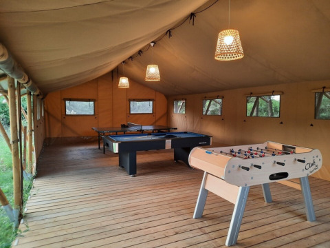 Sala de juegos en tienda en Domaine La Sauzette, Occitanie, Francia, con futbolín, billar y ping pong.