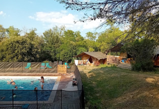 Kinder schwimmen im Pool im Domaine La Sauzette Ferienpark in Okzitanien, Frankreich, umgeben von Natur.