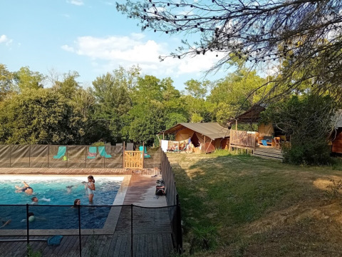 Kinderen zwemmen in het zwembad bij Domaine La Sauzette vakantiepark in Occitanië, Frankrijk, omgeven door groen.