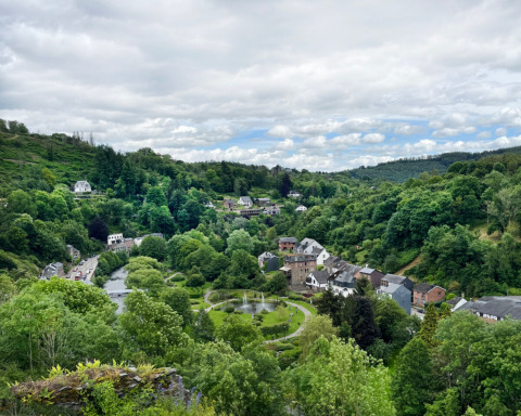 Vista panorámica de colinas verdes, árboles, río y casas en Camping la Roche parque vacacional, Limburgo, Bélgica.