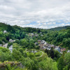 Panoramic view of green hills, river, trees, and houses at Camping la Roche holiday park in Limburg, Belgium.